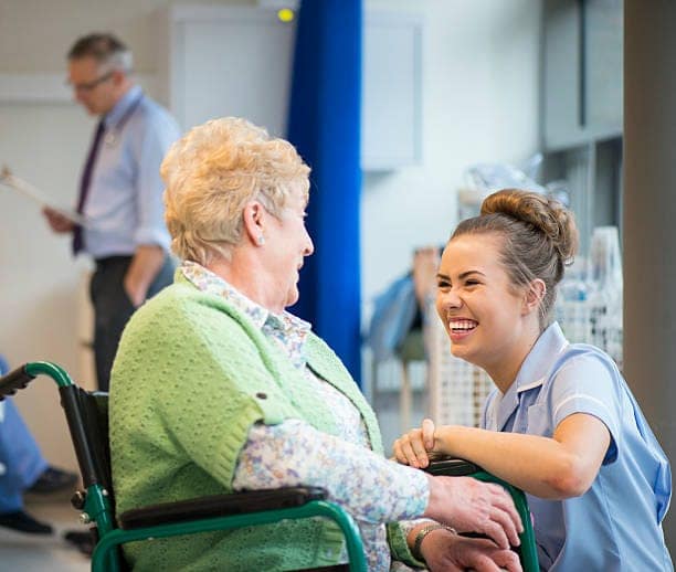 senior woman laughing with nurse on the ward or nursing home New opportunities press